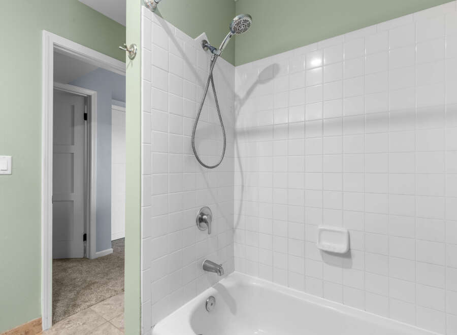 This bathroom features a clean and classic white tiled shower and bathtub combination.