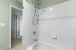 This bathroom features a clean and classic white tiled shower and bathtub combination.