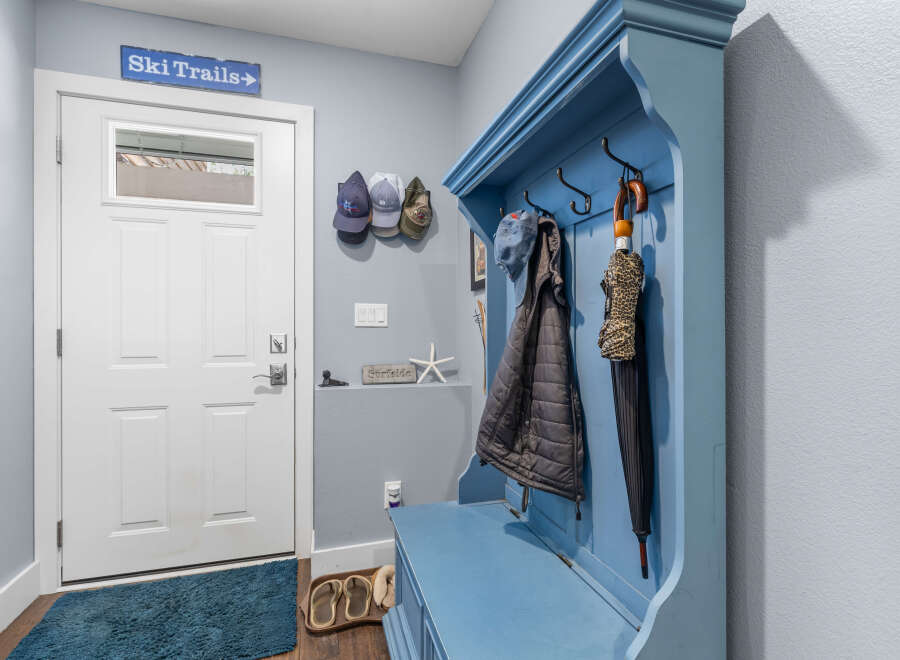 Welcome guests into this charming entryway featuring a bright white door and a cozy blue hall tree.