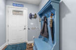 Welcome guests into this charming entryway featuring a bright white door and a cozy blue hall tree.