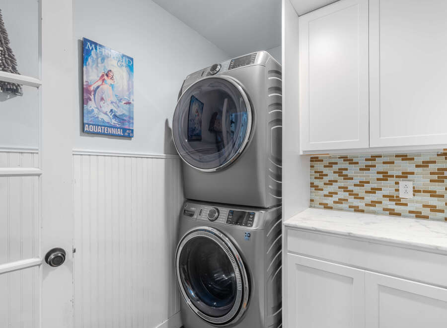 Discover this beautifully appointed laundry room featuring a stacked washer and dryer for space efficiency.