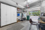 Discover ample storage solutions in this spacious garage, featuring tall white cabinets and open shelving perfect for organizing all your tools and recreational gear.