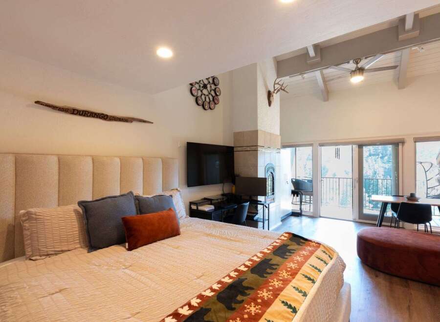 Experience mountain living in this spacious studio featuring a cozy king-sized bed with a plush headboard and a decorative bear-themed throw.