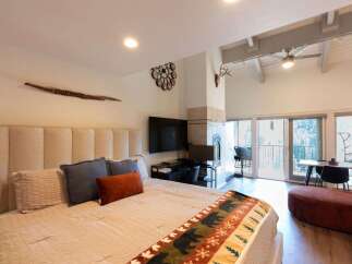 Experience mountain living in this spacious studio featuring a cozy king-sized bed with a plush headboard and a decorative bear-themed throw.