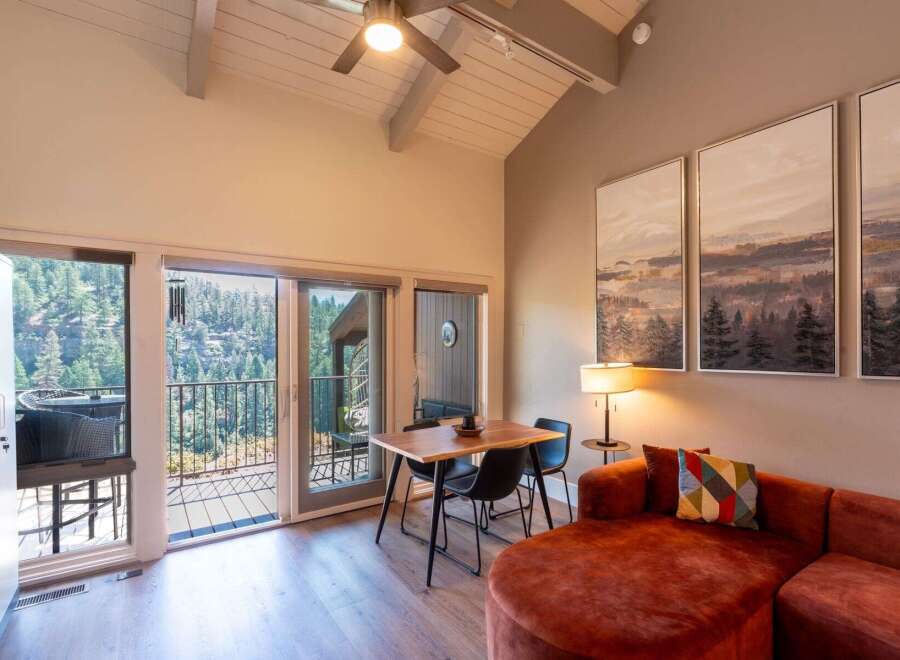 Experience breathtaking mountain views from this stunning living space, featuring a vaulted ceiling with a ceiling fan and large windows that flood the room with natural light.