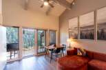 Experience breathtaking mountain views from this stunning living space, featuring a vaulted ceiling with a ceiling fan and large windows that flood the room with natural light.