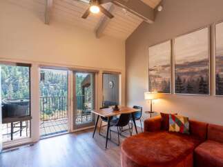 Experience breathtaking mountain views from this stunning living space, featuring a vaulted ceiling with a ceiling fan and large windows that flood the room with natural light.