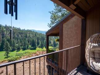Enjoy breathtaking panoramic views from this stunning property, featuring a spacious balcony overlooking a lush green golf course nestled within a dense pine forest.