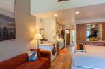 Discover this charming studio apartment featuring a cozy living area with a plush sofa and a vibrant accent pillow.