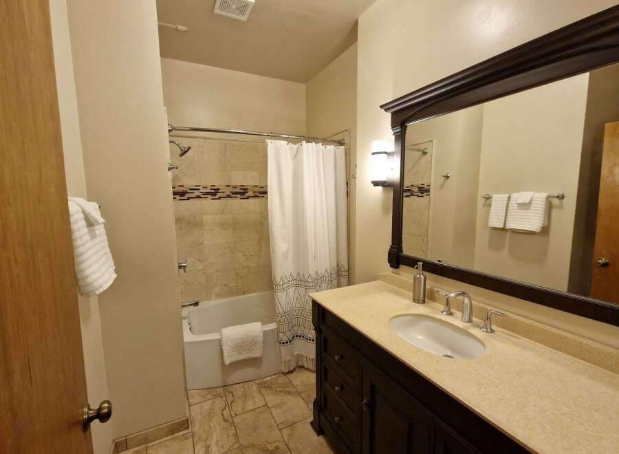 This bathroom features a spacious vanity with a granite countertop and a modern undermount sink, complemented by sleek chrome fixtures.