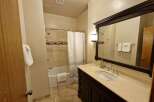 This bathroom features a spacious vanity with a granite countertop and a modern undermount sink, complemented by sleek chrome fixtures.