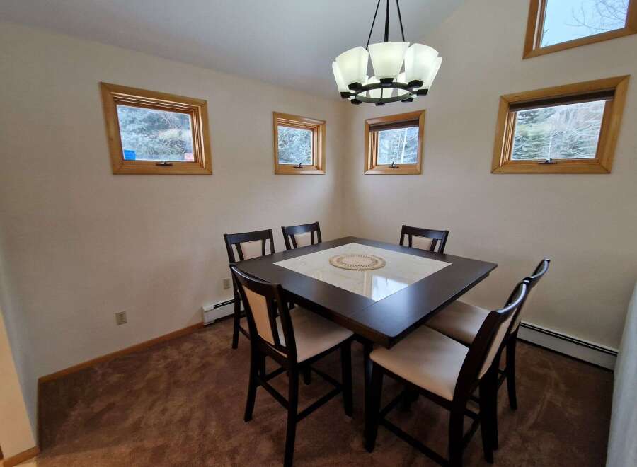 This dining area features a dark wood table with a marble inlay, surrounded by four upholstered chairs, perfect for intimate gatherings.