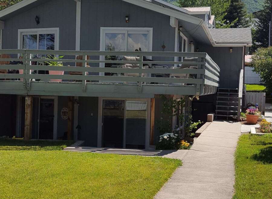 This charming property features a spacious deck perfect for outdoor entertaining, overlooking a lush green lawn.