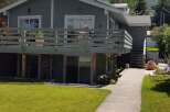 This charming property features a spacious deck perfect for outdoor entertaining, overlooking a lush green lawn.