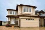 This charming two-story home features a welcoming covered porch with brick accents and a spacious attached garage.