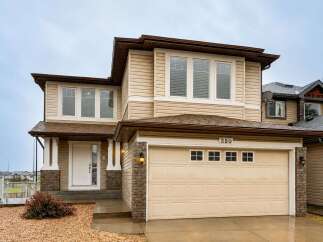 This charming two-story home features a welcoming covered porch with brick accents and a spacious attached garage.