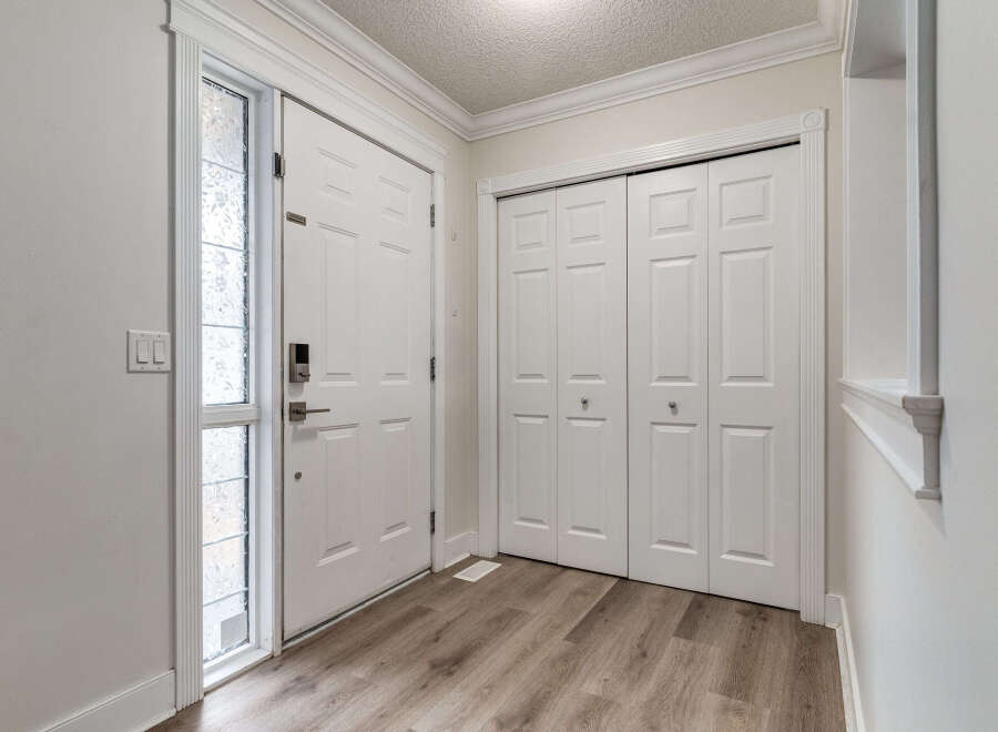 Step into this inviting entryway featuring a modern front door with a sleek digital lock and a decorative glass sidelight.