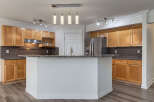 This spacious kitchen features beautiful light wood cabinetry complemented by a dark subway tile backsplash and granite countertops.