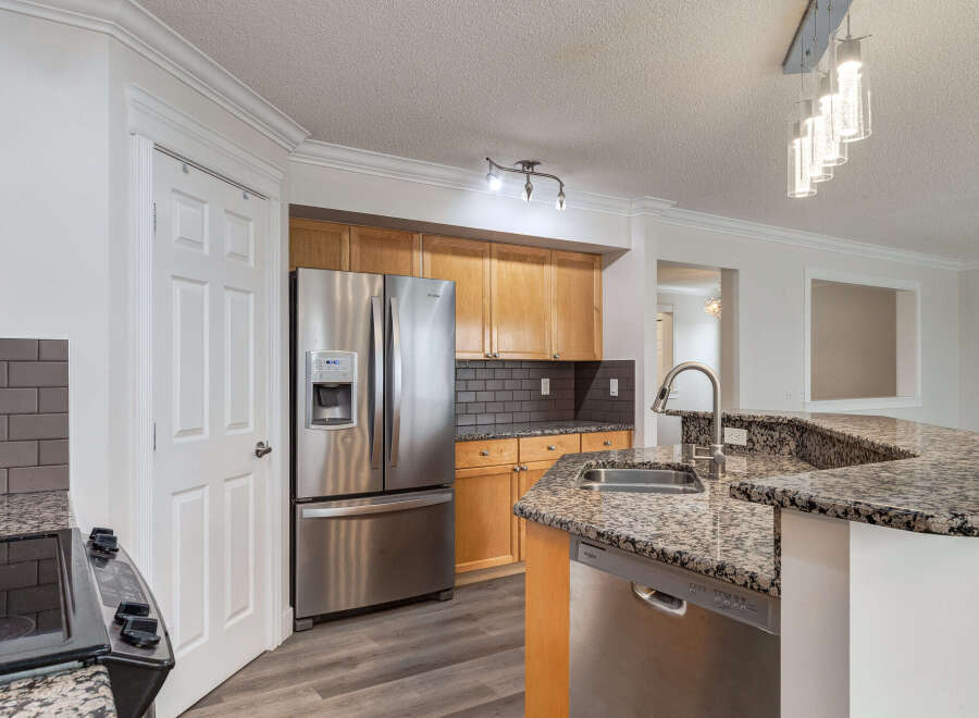 This modern kitchen boasts stainless steel appliances, including a French door refrigerator and a built-in dishwasher.