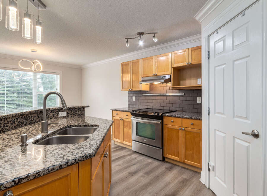 This spacious kitchen boasts granite countertops and a double sink, perfect for meal preparation.