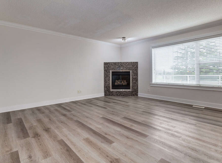 Experience comfort and style in this inviting living space, featuring a striking granite-surround fireplace as the focal point.