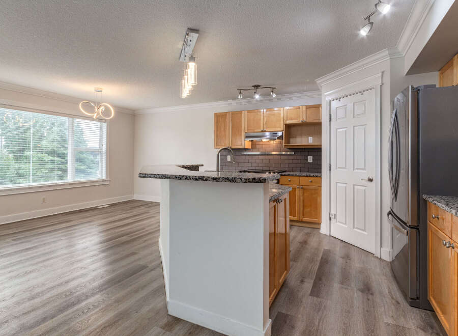 Discover this stunning kitchen and dining area, featuring elegant granite countertops and warm wooden cabinetry.