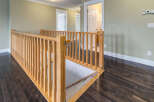 This image showcases a beautifully designed hallway with a wooden banister and dark hardwood floors.