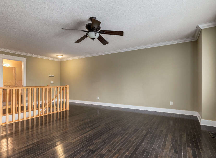 Step into this spacious living area featuring rich, dark hardwood floors that gleam under the recessed lighting and a stylish ceiling fan.