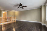 Step into this spacious living area featuring rich, dark hardwood floors that gleam under the recessed lighting and a stylish ceiling fan.