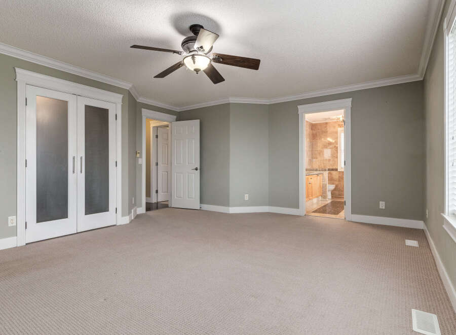 Step into this spacious bedroom featuring a ceiling fan for comfort and elegant crown molding throughout.