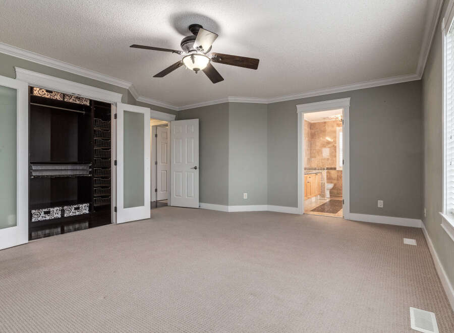 Step into this spacious master bedroom featuring a large walk-in closet with ample storage and a ceiling fan for comfort.