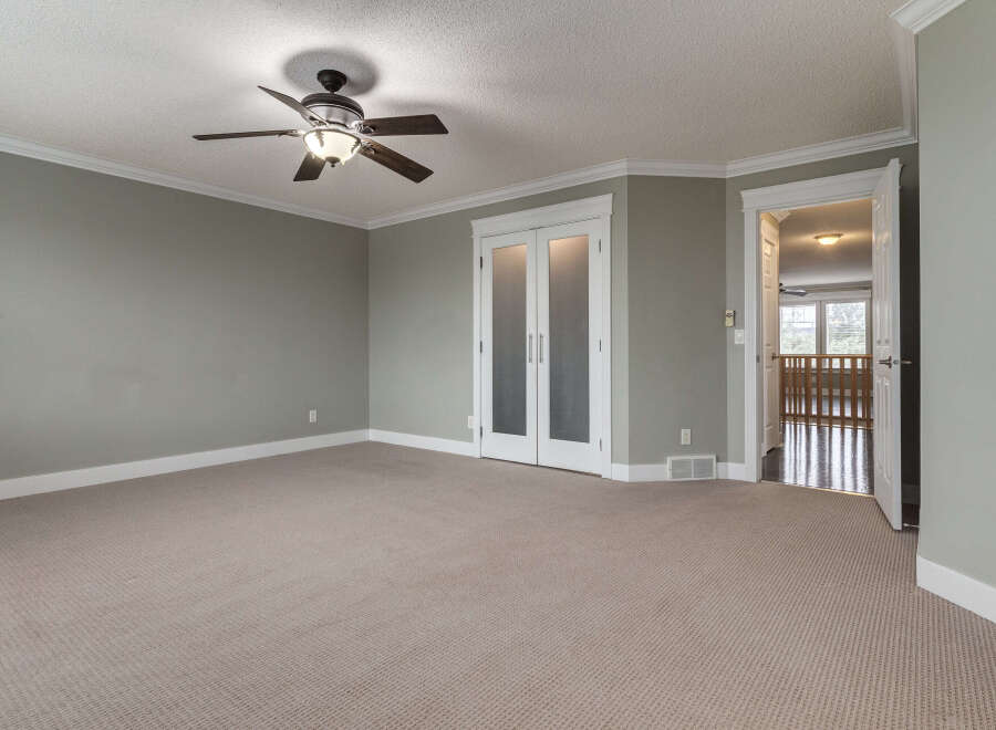 Step into this spacious room featuring a neutral carpet and a modern ceiling fan for comfort.