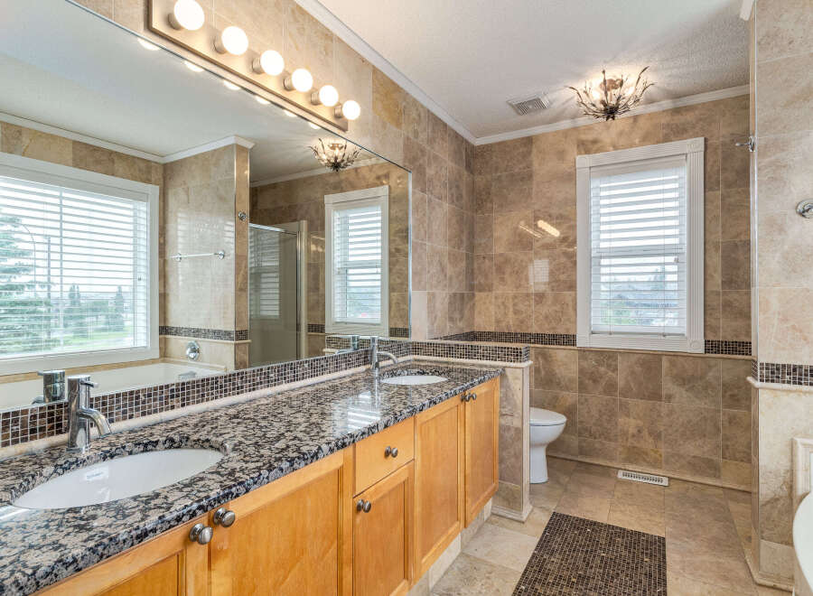 Indulge in luxury with this stunning bathroom featuring a spacious double vanity with granite countertops and elegant wood cabinetry.