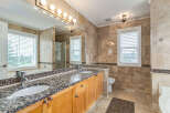 Indulge in luxury with this stunning bathroom featuring a spacious double vanity with granite countertops and elegant wood cabinetry.