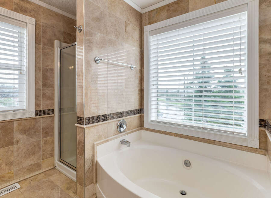 Indulge in luxury with this stunning bathroom featuring a spacious jacuzzi tub and a separate glass-enclosed shower.