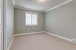 This empty room features a neutral color palette with light gray walls and a beige carpeted floor, creating a versatile canvas for any decor style.