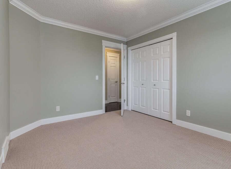 This spacious room features a neutral carpet and light green walls, creating a serene atmosphere.