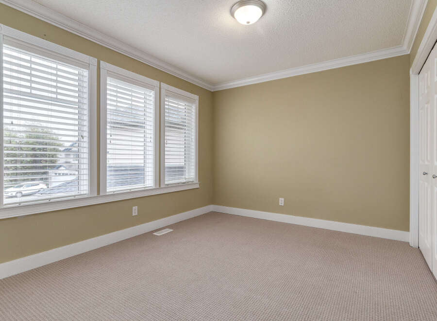 This empty room features a neutral color palette with beige walls and carpet, creating a versatile space.