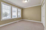 This empty room features a neutral color palette with beige walls and carpet, creating a versatile space.