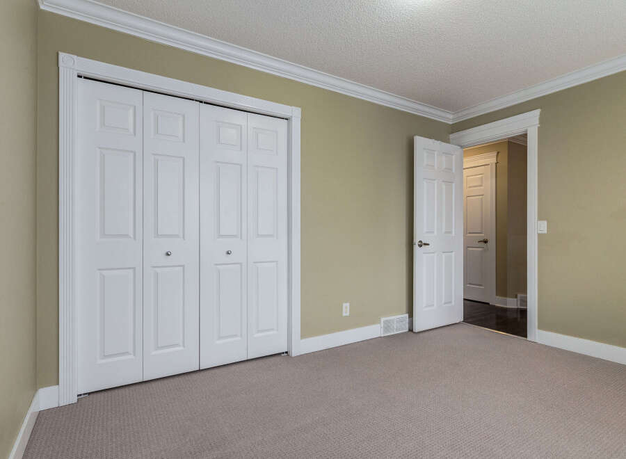 This spacious room features a large double door closet with elegant trim, perfect for ample storage.