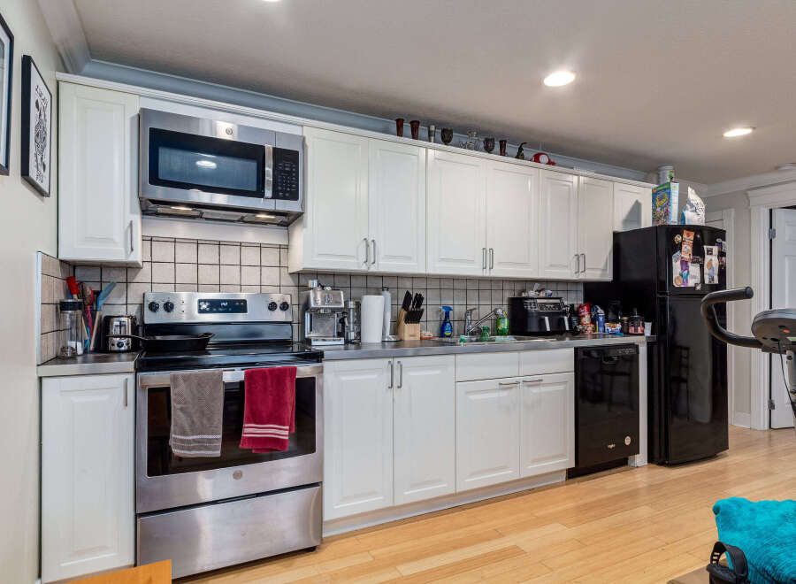 Discover this charming kitchen featuring sleek stainless steel appliances, including a microwave, oven, and dishwasher, complemented by ample white cabinetry for storage.