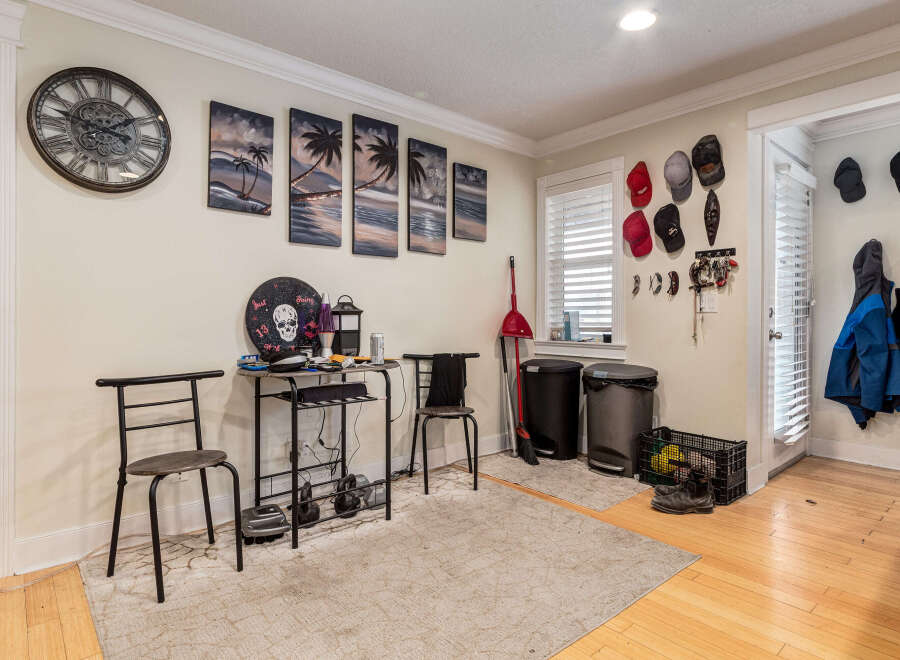 This entryway offers a blend of functionality and decorative flair, featuring a large wall clock and a series of tropical-themed paintings.