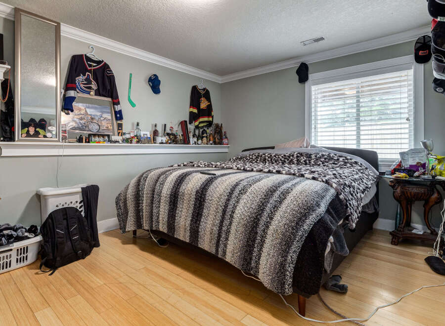 This bedroom offers a cozy and personalized retreat, featuring a comfortable bed adorned with a striped blanket.