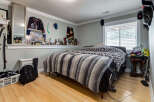 This bedroom offers a cozy and personalized retreat, featuring a comfortable bed adorned with a striped blanket.