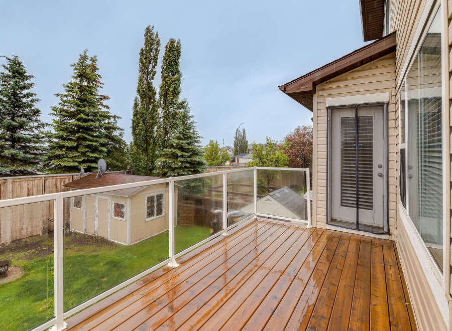 Enjoy outdoor living on this spacious wooden deck, complete with a modern glass railing for unobstructed views of the backyard.