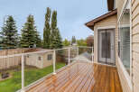 Enjoy outdoor living on this spacious wooden deck, complete with a modern glass railing for unobstructed views of the backyard.