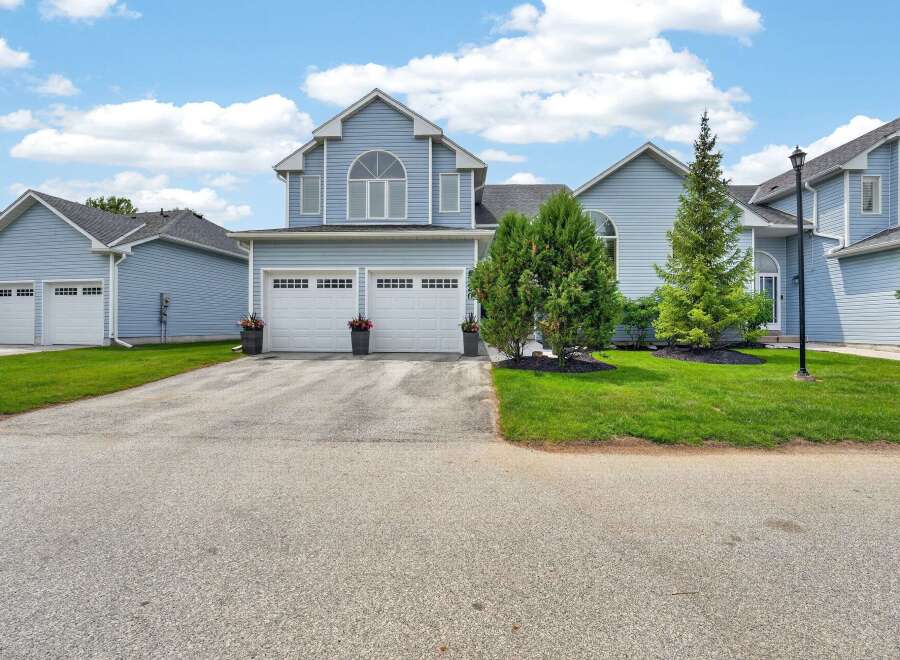 This stunning light blue townhouse boasts a charming arched window above a double garage with white doors.