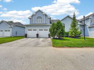 This stunning light blue townhouse boasts a charming arched window above a double garage with white doors.