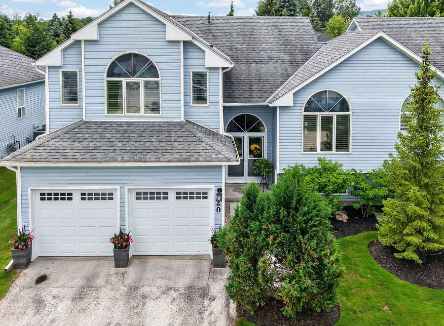 Discover this charming light blue home featuring a spacious two-car garage and elegant arched windows.