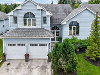 Discover this charming light blue home featuring a spacious two-car garage and elegant arched windows.